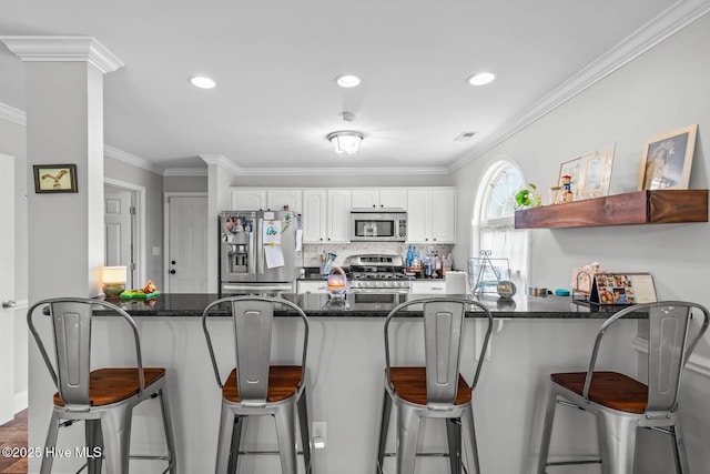 912 Morganser Dr, Swansboro, NC 28584 - kitchen featuring appliances with stainless steel finishes, a peninsula, dark stone countertops, ornamental molding, and white cabinetry