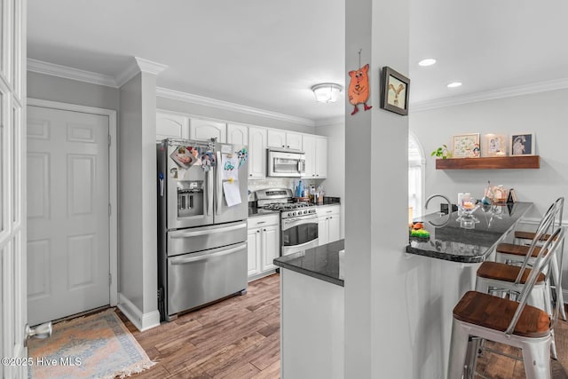 912 Morganser Dr, Swansboro, NC 28584 - kitchen featuring stainless steel appliances, a kitchen breakfast bar, white cabinetry, light wood-style flooring, and recessed lighting