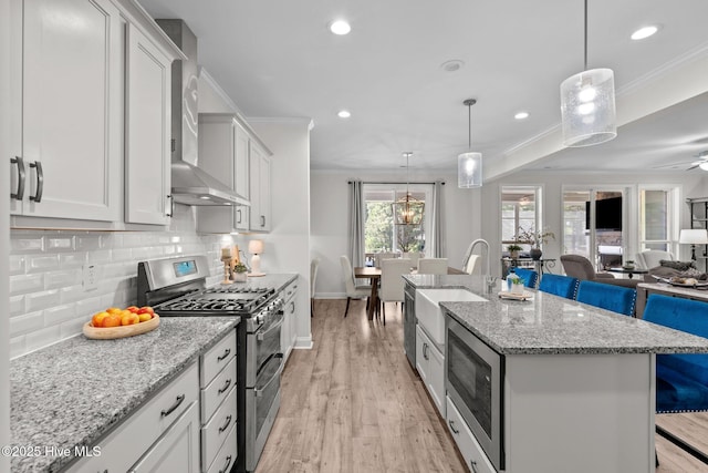106 Josephs Pt, West End, NC 27376 - kitchen with stainless steel appliances, a sink, wall chimney range hood, backsplash, and open floor plan