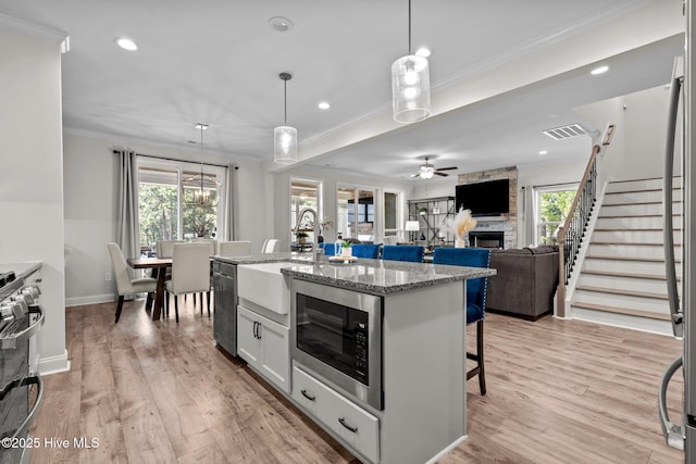 106 Josephs Pt, West End, NC 27376 - kitchen featuring a sink, appliances with stainless steel finishes, a stone fireplace, crown molding, and a ceiling fan