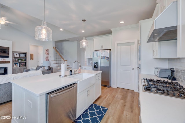 5920 Appomattox Dr, Wilmington, NC 28409 - kitchen featuring appliances with stainless steel finishes, open floor plan, range hood, a sink, and white cabinets