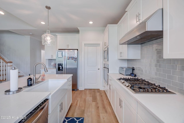5920 Appomattox Dr, Wilmington, NC 28409 - kitchen with under cabinet range hood, stainless steel appliances, white cabinetry, decorative backsplash, and light countertops