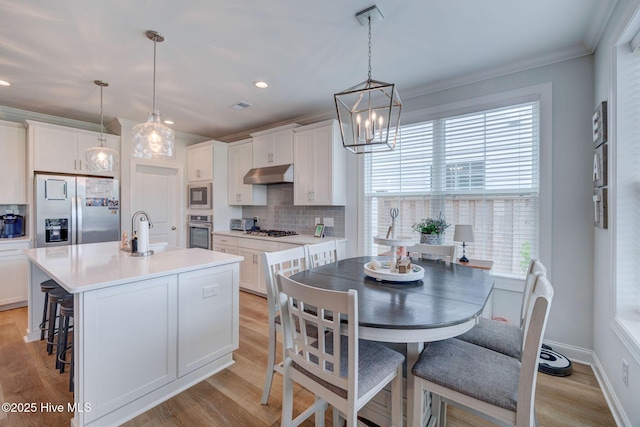 5920 Appomattox Dr, Wilmington, NC 28409 - kitchen featuring stainless steel appliances, under cabinet range hood, tasteful backsplash, healthy amount of natural light, and ornamental molding