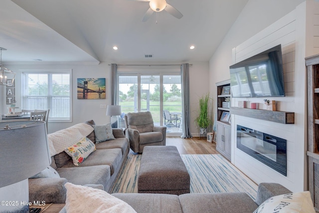 5920 Appomattox Dr, Wilmington, NC 28409 - living area featuring vaulted ceiling, a glass covered fireplace, light wood-style flooring, a ceiling fan, and a chandelier