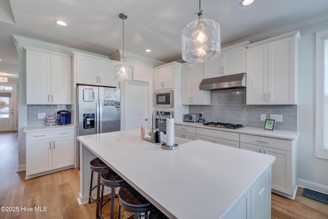 5920 Appomattox Dr, Wilmington, NC 28409 - kitchen featuring under cabinet range hood, stainless steel gas cooktop, white cabinets, crown molding, and recessed lighting