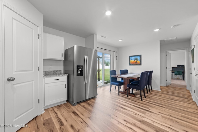 3402 Woodwind Ct, Kinston, NC 28504 - kitchen with stainless steel refrigerator with ice dispenser, light wood-style floors, white cabinets, recessed lighting, and light stone counters