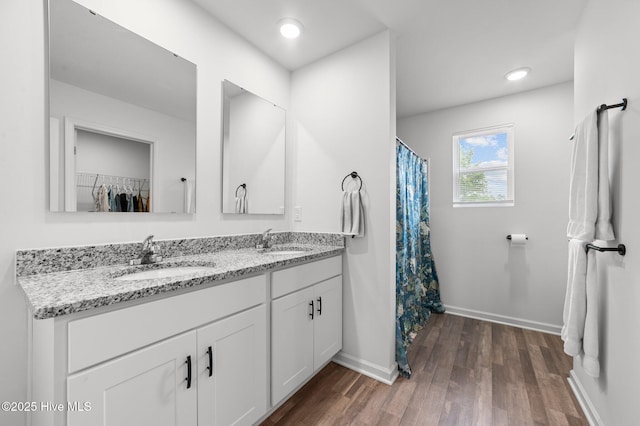 3402 Woodwind Ct, Kinston, NC 28504 - full bathroom featuring baseboards, wood finished floors, double vanity, a shower with shower curtain, and a spacious closet