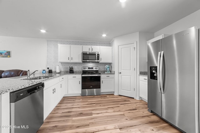 3402 Woodwind Ct, Kinston, NC 28504 - kitchen with appliances with stainless steel finishes, a sink, white cabinetry, light stone countertops, and light wood finished floors