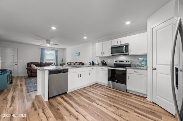 3402 Woodwind Ct, Kinston, NC 28504 - kitchen featuring appliances with stainless steel finishes, open floor plan, white cabinets, a peninsula, and recessed lighting