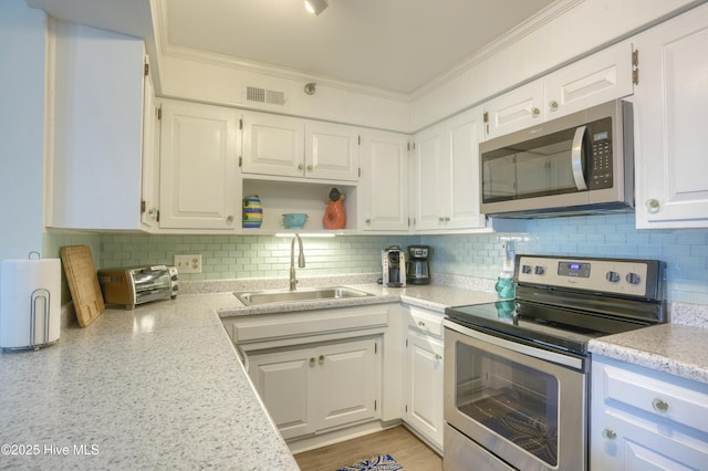 1896 New River Inlet Rd Unit 1212, North Topsail Beach, NC 28460 - kitchen with stainless steel appliances, a sink, white cabinetry, ornamental molding, and tasteful backsplash