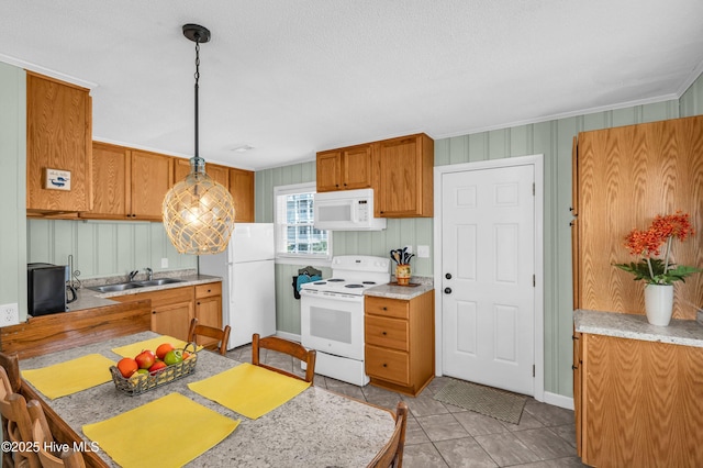 1020 Carolina Beach Ave N, Carolina Beach, NC 28428 - kitchen featuring white appliances, light countertops, brown cabinets, decorative light fixtures, and light tile patterned floors