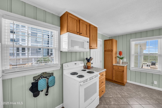 1020 Carolina Beach Ave N, Carolina Beach, NC 28428 - kitchen featuring white appliances, plenty of natural light, light countertops, a textured ceiling, and brown cabinetry