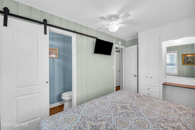 1020 Carolina Beach Ave N, Carolina Beach, NC 28428 - bedroom featuring a barn door, ornamental molding, ensuite bath, and ceiling fan