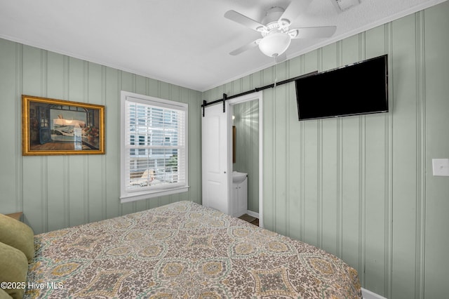 1020 Carolina Beach Ave N, Carolina Beach, NC 28428 - bedroom with ornamental molding, a barn door, a decorative wall, ensuite bathroom, and ceiling fan