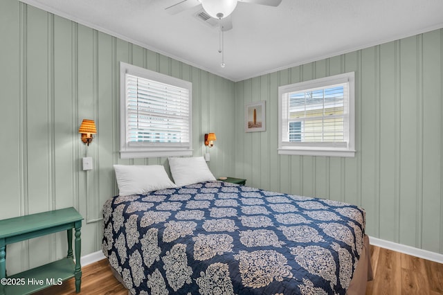 1020 Carolina Beach Ave N, Carolina Beach, NC 28428 - bedroom featuring ornamental molding, multiple windows, wood finished floors, and a ceiling fan