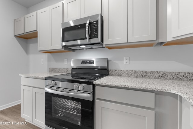 250 Arnette Dr Unit 83B, Ocean Isle Beach, NC 28469 - kitchen featuring stainless steel appliances, light wood finished floors, light stone countertops, and baseboards