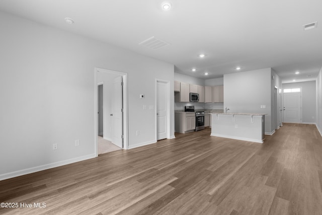 250 Arnette Dr Unit 83B, Ocean Isle Beach, NC 28469 - unfurnished living room featuring recessed lighting, baseboards, light wood-type flooring, and a sink