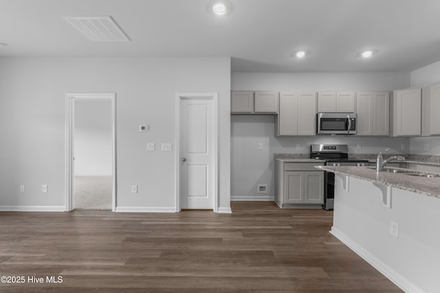250 Arnette Dr Unit 83B, Ocean Isle Beach, NC 28469 - kitchen featuring appliances with stainless steel finishes, a sink, light stone counters, gray cabinets, and dark wood-style floors