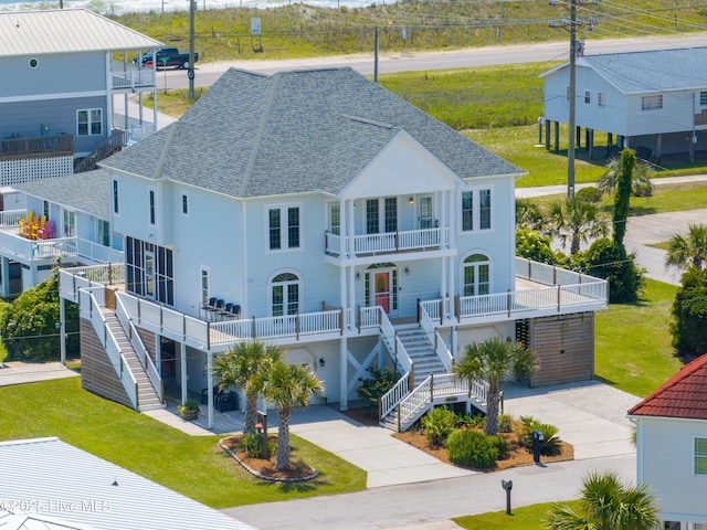 306 Marina Way N, Topsail Beach, NC 28460 - back of property with a balcony, stairs, a shingled roof, a lawn, and concrete driveway