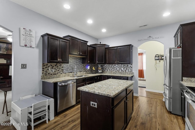 700 Stafford Ln, Jacksonville, NC 28546 - kitchen featuring appliances with stainless steel finishes, a sink, arched walkways, backsplash, and dark brown cabinetry