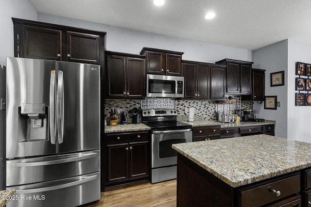 700 Stafford Ln, Jacksonville, NC 28546 - kitchen with stainless steel appliances, backsplash, light stone counters, light wood-style floors, and a center island