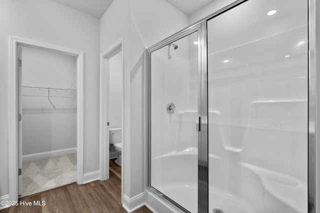 254 Arnette Dr Unit 82B, Shallotte, NC 28469 - bathroom featuring wood finished floors, a shower stall, toilet, a walk in closet, and baseboards