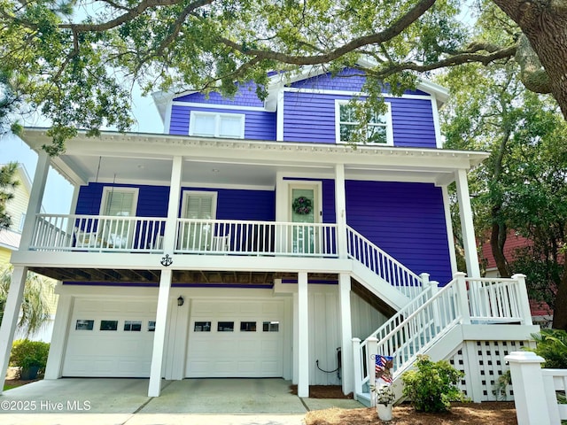 240 Seawatch Way, Kure Beach, NC 28449 - coastal inspired home featuring covered porch, an attached garage, board and batten siding, stairs, and concrete driveway