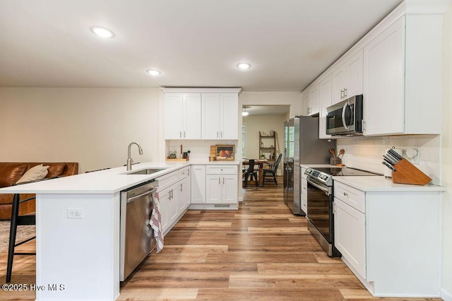1809 E Indiana Ave, Southern Pines, NC 28387 - kitchen with stainless steel appliances, a peninsula, a sink, light wood finished floors, and a kitchen breakfast bar
