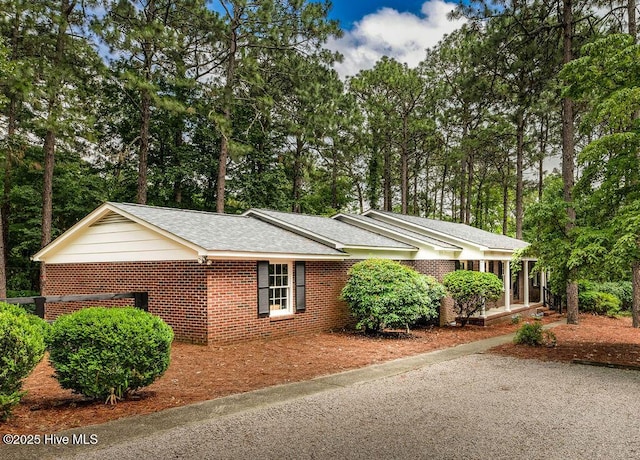 1809 E Indiana Ave, Southern Pines, NC 28387 - view of property exterior with brick siding, view of wooded area, and a shingled roof