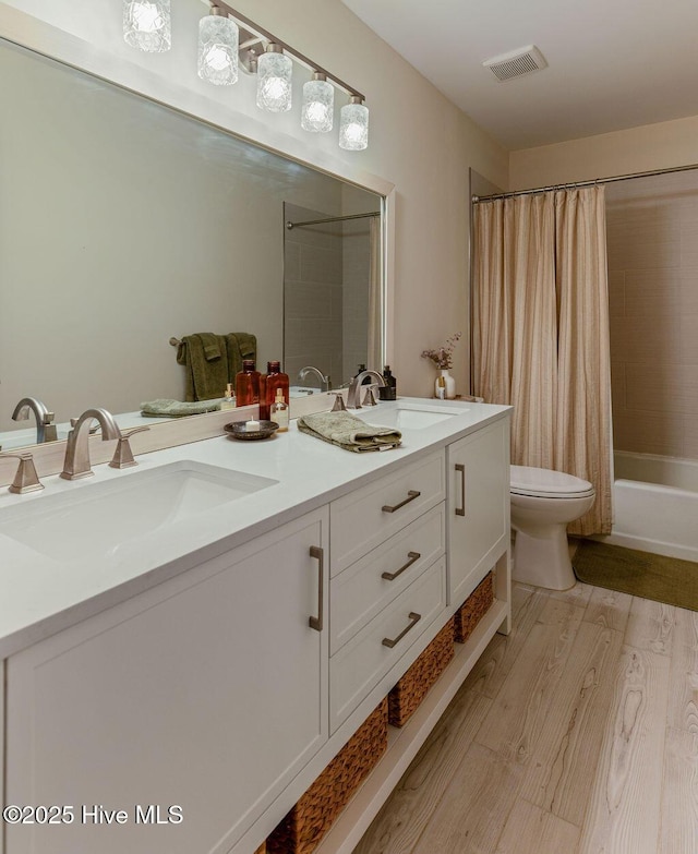 1809 E Indiana Ave, Southern Pines, NC 28387 - bathroom with double vanity, wood finished floors, toilet, and shower / tub combo with curtain