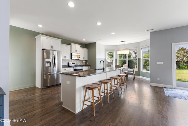 737 Heartwood Dr, Leland, NC 28479 - kitchen with appliances with stainless steel finishes, a center island with sink, backsplash, baseboards, and white cabinetry