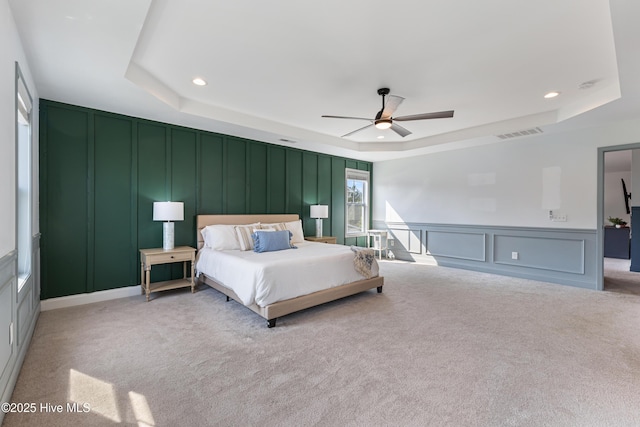 737 Heartwood Dr, Leland, NC 28479 - bedroom with a decorative wall, a tray ceiling, light carpet, recessed lighting, and a ceiling fan