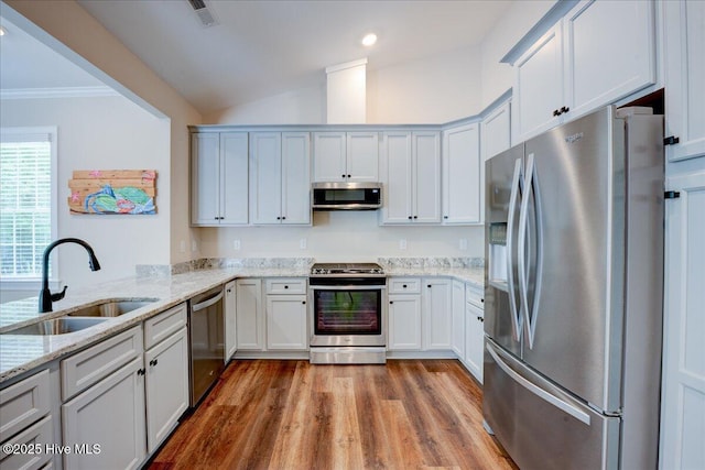 409 Kinnakeet Ln, New Bern, NC 28562 - kitchen with stainless steel appliances, a sink, wood finished floors, vaulted ceiling, and light stone countertops