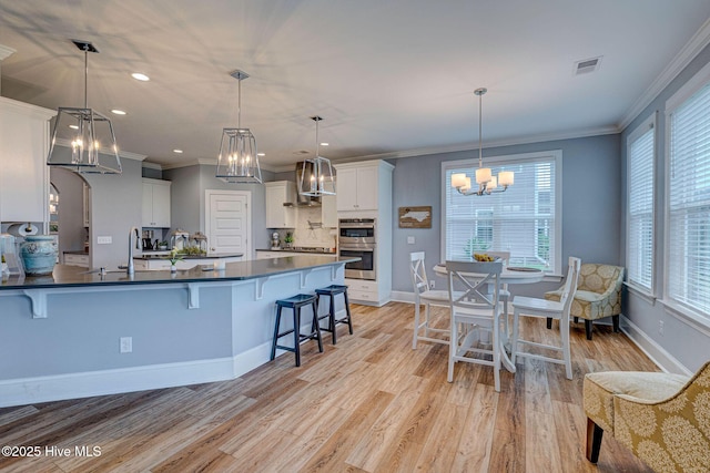 1279 Pandion Dr, Wilmington, NC 28411 - kitchen featuring a chandelier, dark countertops, stainless steel double oven, wall chimney range hood, and ornamental molding