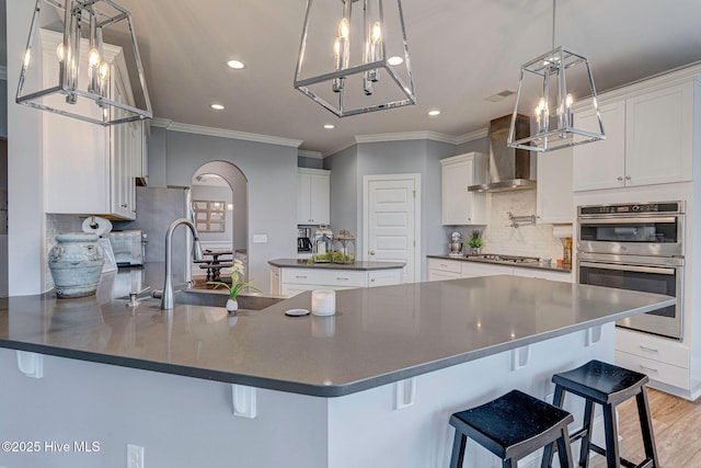1279 Pandion Dr, Wilmington, NC 28411 - kitchen featuring a chandelier, wall chimney range hood, dark countertops, a peninsula, and stainless steel appliances