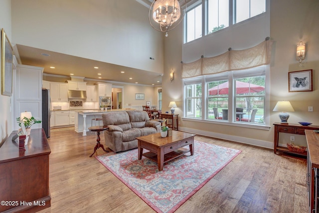 7406 Songbird Ct, Wilmington, NC 28411 - living room with healthy amount of natural light, light wood finished floors, a high ceiling, a chandelier, and baseboards