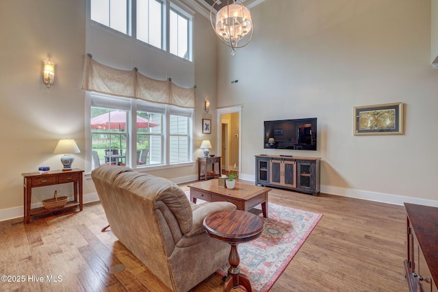 7406 Songbird Ct, Wilmington, NC 28411 - living room featuring light wood-style flooring, plenty of natural light, a chandelier, baseboards, and a towering ceiling