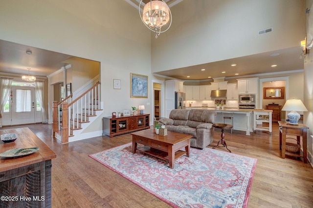7406 Songbird Ct, Wilmington, NC 28411 - living area with a chandelier, crown molding, light wood-type flooring, a high ceiling, and stairs