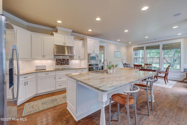 7406 Songbird Ct, Wilmington, NC 28411 - kitchen featuring under cabinet range hood, crown molding, stainless steel appliances, a sink, and white cabinets