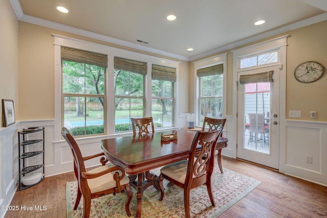 7406 Songbird Ct, Wilmington, NC 28411 - dining room with crown molding, a decorative wall, a wainscoted wall, light wood-style floors, and plenty of natural light
