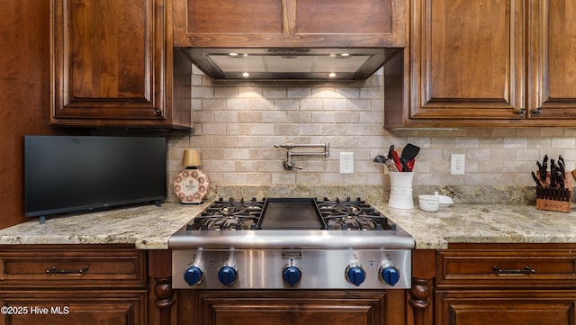 370 Lake Dornoch Dr, Pinehurst, NC 28374 - kitchen with range hood, stainless steel gas stovetop, backsplash, and light stone countertops