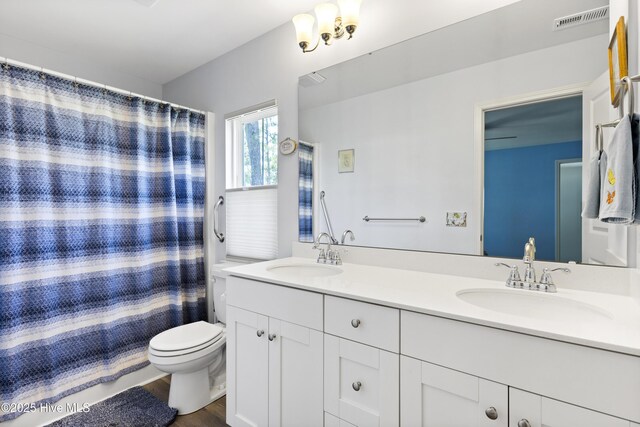 940 Pine Needles Rd, Southport, NC 28461 - full bath featuring double vanity, toilet, wood finished floors, and a shower with curtain