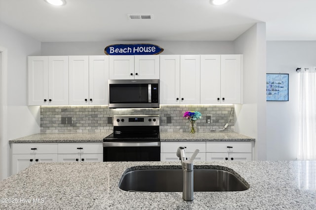 940 Pine Needles Rd, Southport, NC 28461 - kitchen with electric range, stainless steel microwave, white cabinets, a sink, and recessed lighting