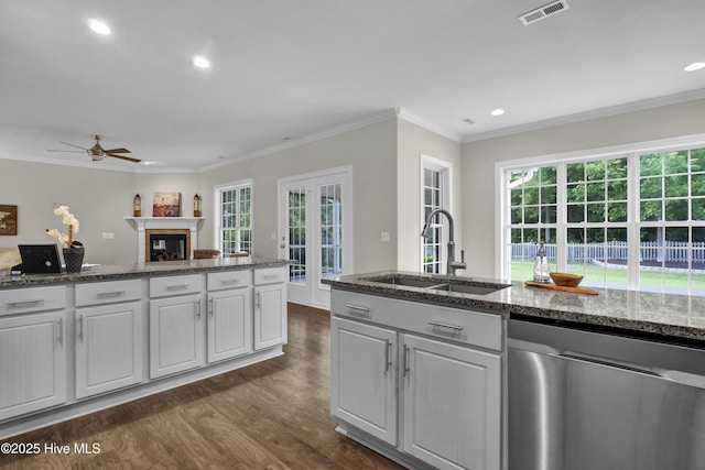 1113 Foxbow Cv, Leland, NC 28451 - kitchen featuring stainless steel dishwasher, a sink, dark wood-style floors, a glass covered fireplace, and ceiling fan