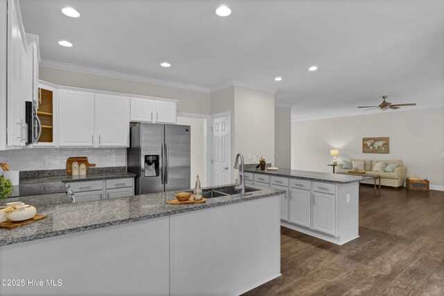 1113 Foxbow Cv, Leland, NC 28451 - kitchen featuring appliances with stainless steel finishes, a peninsula, ornamental molding, dark stone countertops, and white cabinets