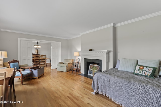 405 E Westbrook St, Wallace, NC 28466 - bedroom featuring crown molding, light wood-style flooring, a fireplace with flush hearth, and a chandelier