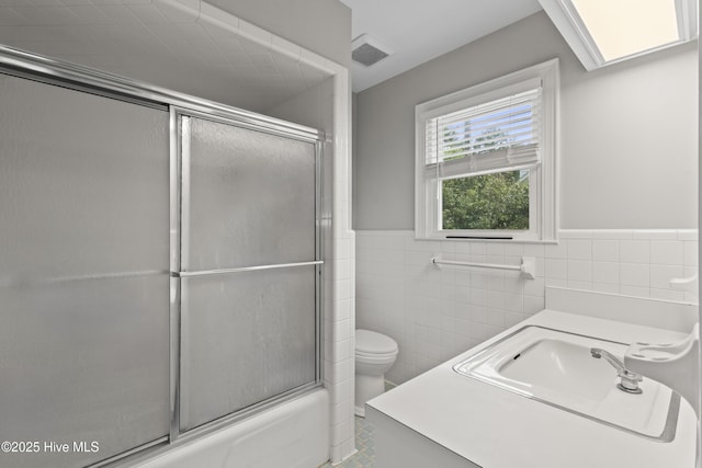 405 E Westbrook St, Wallace, NC 28466 - full bathroom with tile walls, toilet, a wainscoted wall, bath / shower combo with glass door, and vanity