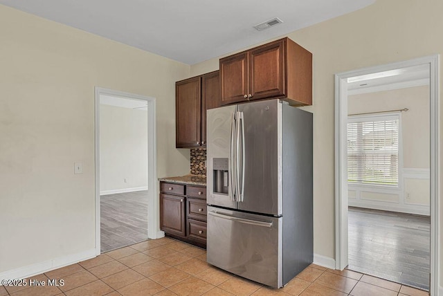 127 Moonstone Ct, Jacksonville, NC 28546 - kitchen with stainless steel fridge with ice dispenser, light tile patterned flooring, tasteful backsplash, baseboards, and stone countertops