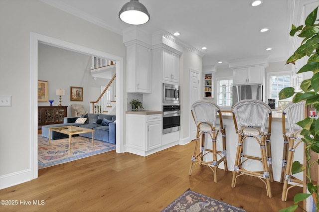 2122 Airlie Brook Dr, Wilmington, NC 28403 - kitchen with stainless steel appliances, crown molding, light wood-type flooring, white cabinets, and recessed lighting