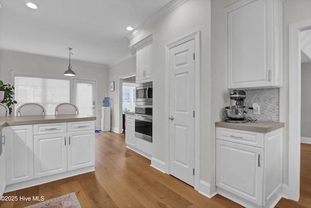 2122 Airlie Brook Dr, Wilmington, NC 28403 - kitchen with appliances with stainless steel finishes, crown molding, light wood-type flooring, decorative backsplash, and white cabinetry